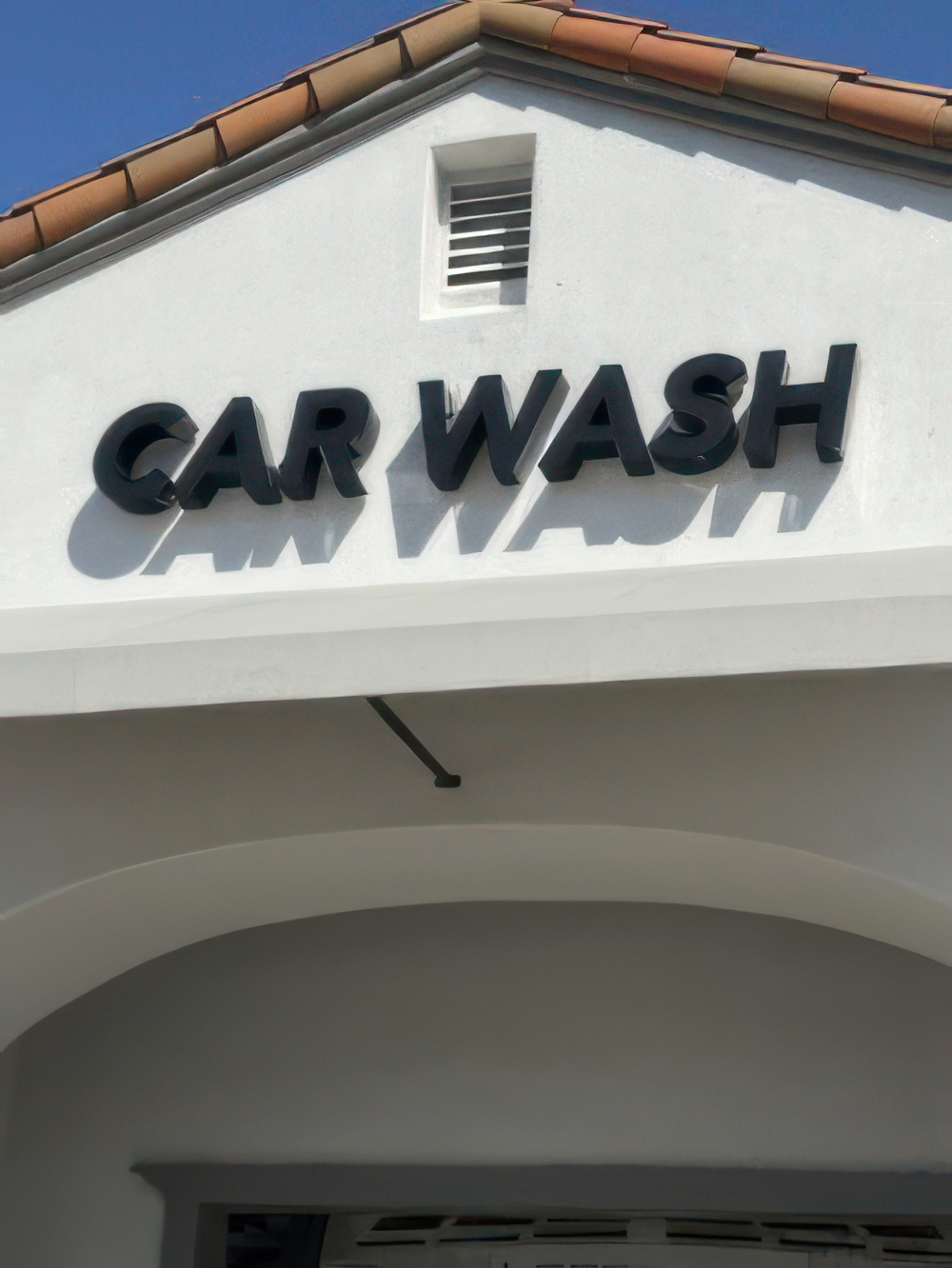 Exterior Commercial Painting for Car Wash Businesses Close up of a freshly painted white commercial building with a bold 'CAR WASH' sign on its facade.