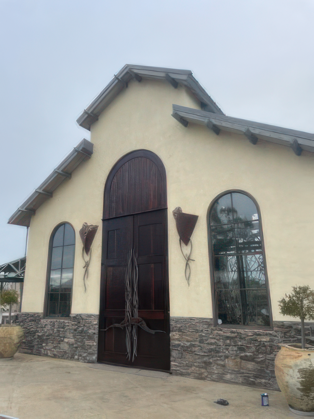Expert Exterior Painting for Stucco Buildings and Commercial Properties Cream stucco exterior of a commercial building with dark wood doors and stone foundation, highlighting professional painting services.