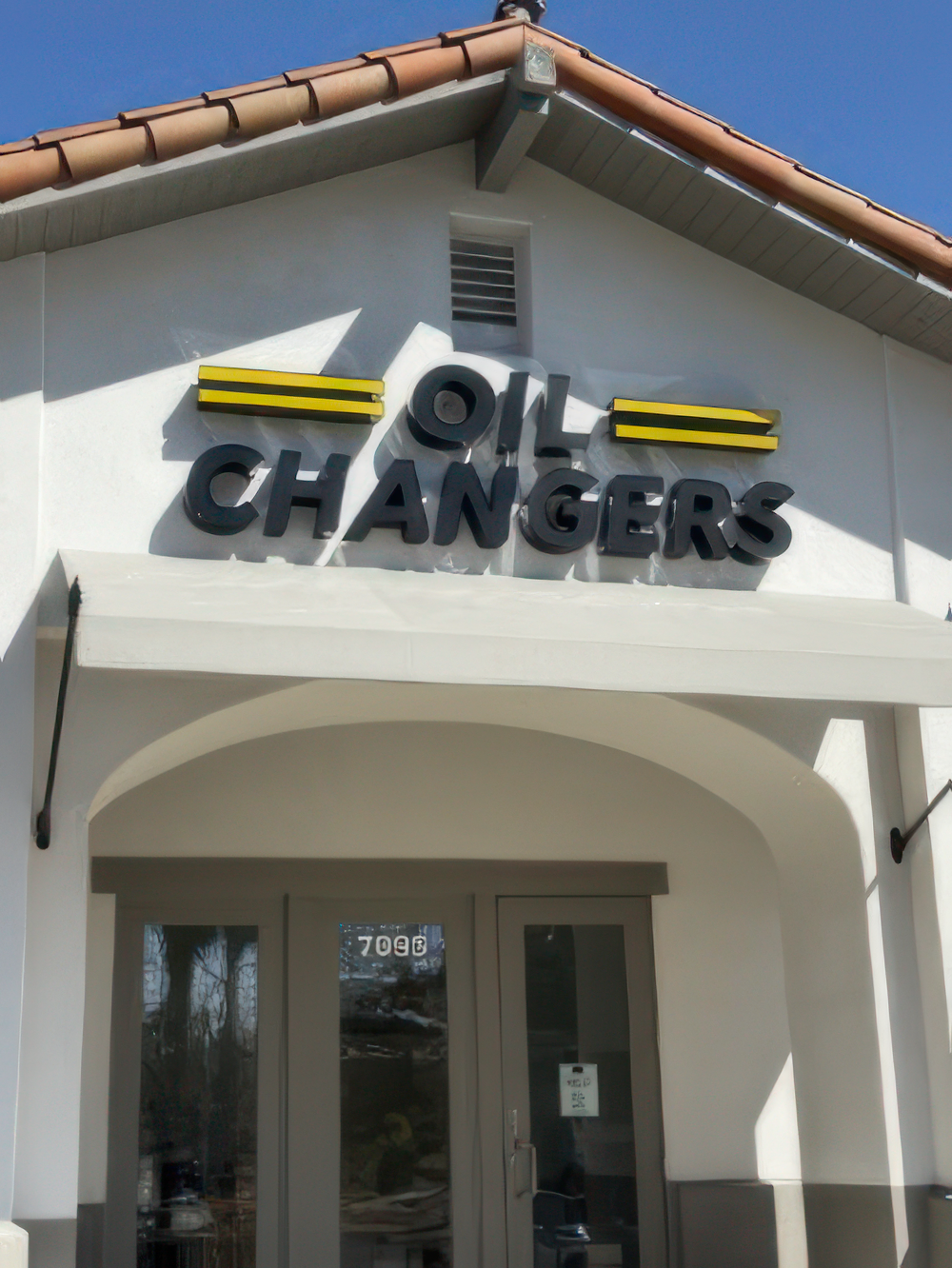 Commercial Exterior Painting for Auto Service Centers A newly painted commercial building with an 'OIL CHANGERS' sign and an awning above the entrance.
