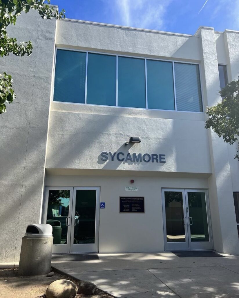 Professional Commercial Office Building Exterior Painting Modern commercial building exterior with SYCAMORE signage, freshly painted cream walls and large windows.