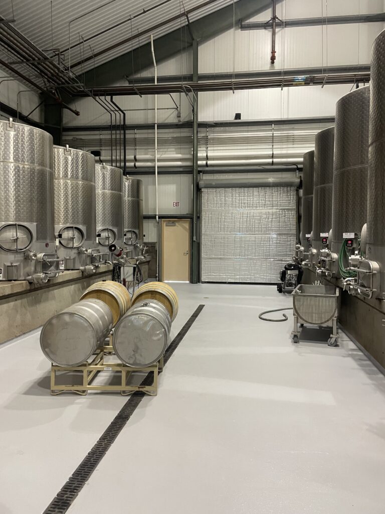 Industrial Interior Painting for Wineries and Commercial Facilities Clean interior of a winery or brewery with stainless steel tanks and freshly painted light gray epoxy floor.