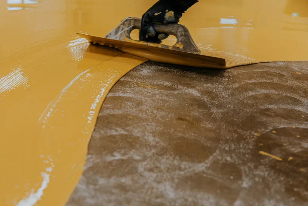 Worker troweling epoxy floor finish gold metallic color Epoxy floor finish trowel application