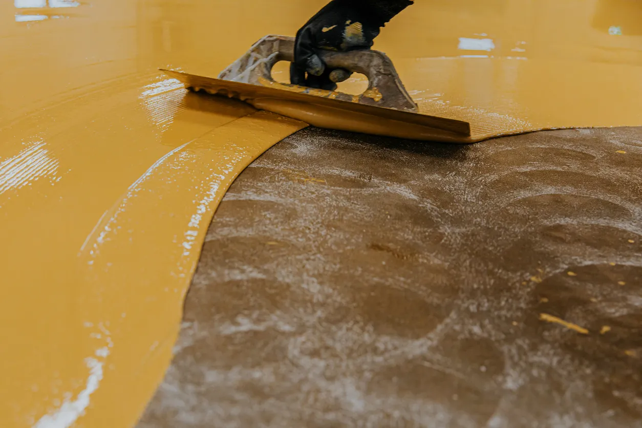 Worker troweling epoxy floor finish gold metallic color Epoxy floor finish trowel application