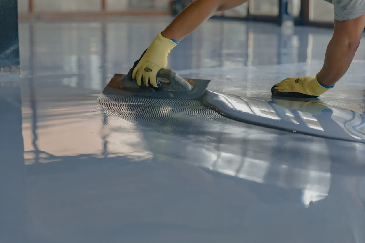 Worker squeegeeing epoxy floor coating commercial installation Epoxy floor squeegee application